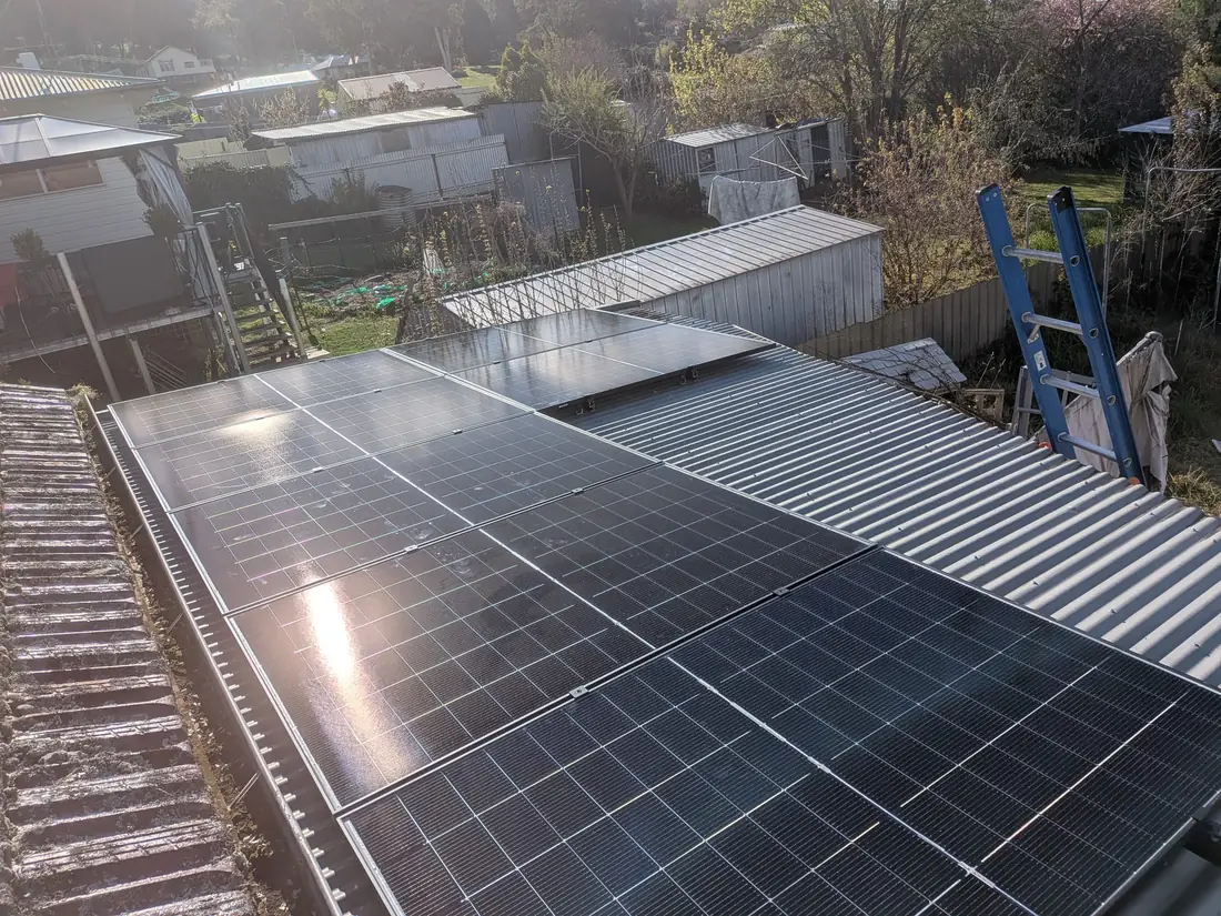 Rows of Blooming Rays solar panels across a tile and tin roof in afternoon light